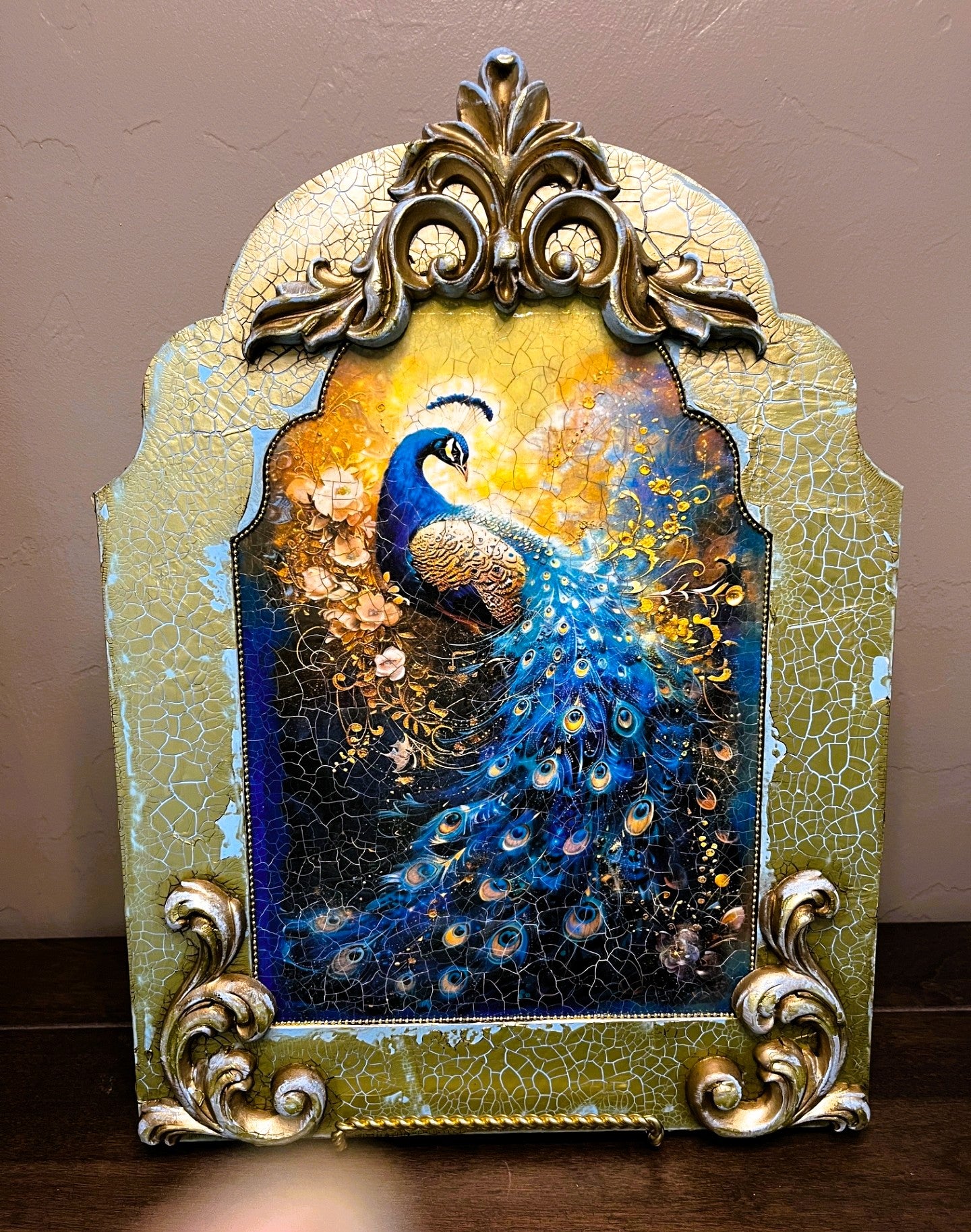 Decorative mirror with a peacock design and ornate frame on a plain background